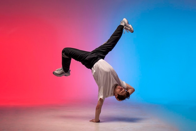 Фото Танцовщица делает акробатический трюк и танцует брейк-данс в неоновом красно-голубом освещении