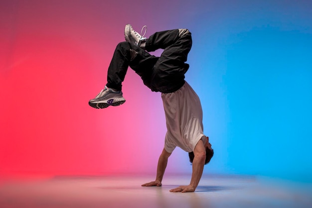 Ballerina che fa trucchi acrobatici e danza breakdance sotto luci al neon rosso e blu