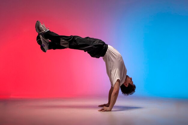 dancer doing acrobatic trick and dancing breakdance in neon red and blue lighting