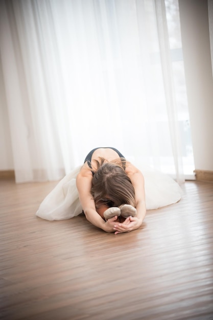 Dancer doing stretching while sitting on the floor in the studio