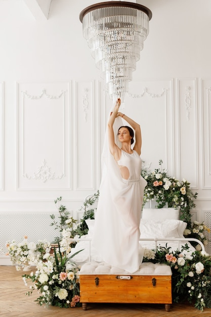 Dancer girl in white dress by the bed in the photo studio