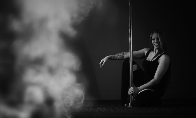 The dancer on the pylon in the studio. Girl doing exercises on a sports equipment.