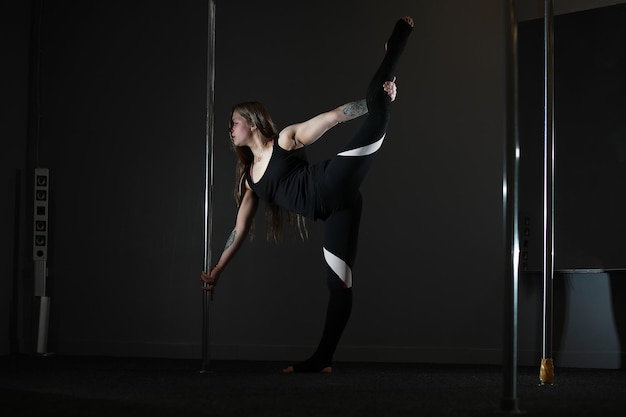 Танцовщица на пилоне в студии Девушка делает упражнения на спортивном снаряде