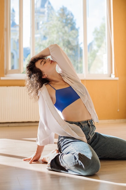 Dancer young girl in casual clothes dancing contemporary dance
indoors the hall in morning sun lights