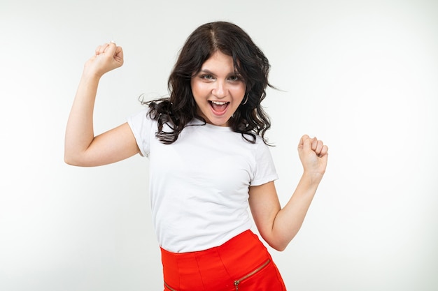 Dancing brunette girl in a white t-shirt comes off to music isolated on a white background.