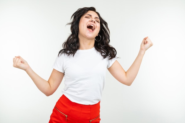 Dancing brunette woman in a white t-shirt comes off to music isolated