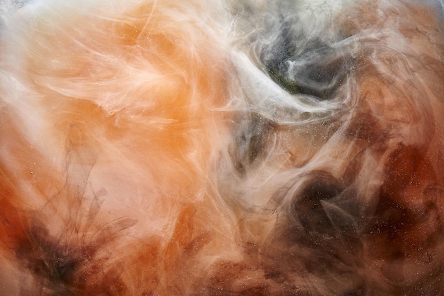 煙の抽象的な背景のカラフルなオレンジ色の渦巻きを踊る混合液体塗料明るいジューシーな顔料のデザイン