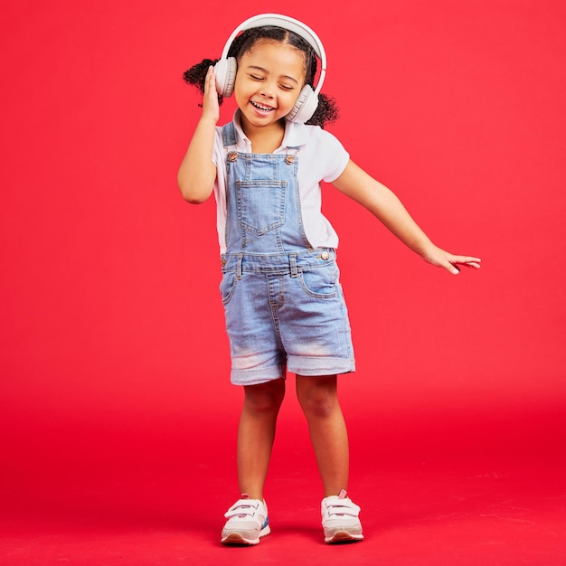 Dancing energy or little girl on music headphones fun radio or childrem podcast on isolated red background Smile happy or dancer kid listening to audio sound and streaming media on studio mockup