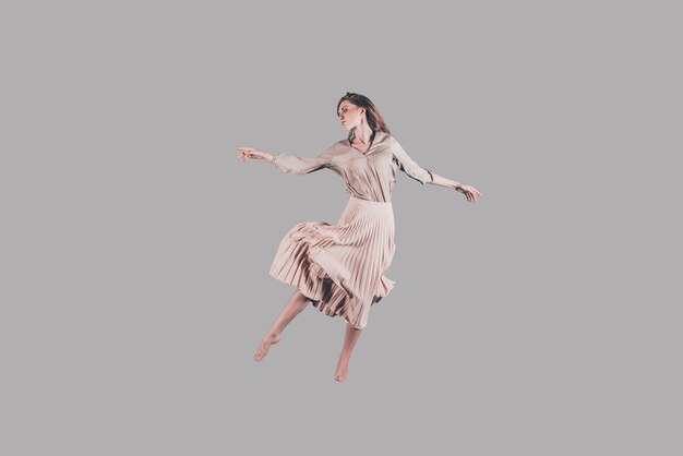 Dancing queen. Studio shot of attractive young woman in beautiful dress hovering in air