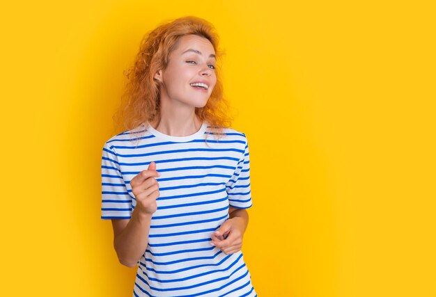 Dancing redhead woman portrait isolated on yellow background portrait of young redhead woman