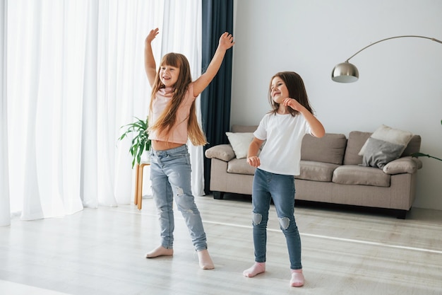 Photo dancing together kids having fun in the domestic room at daytime