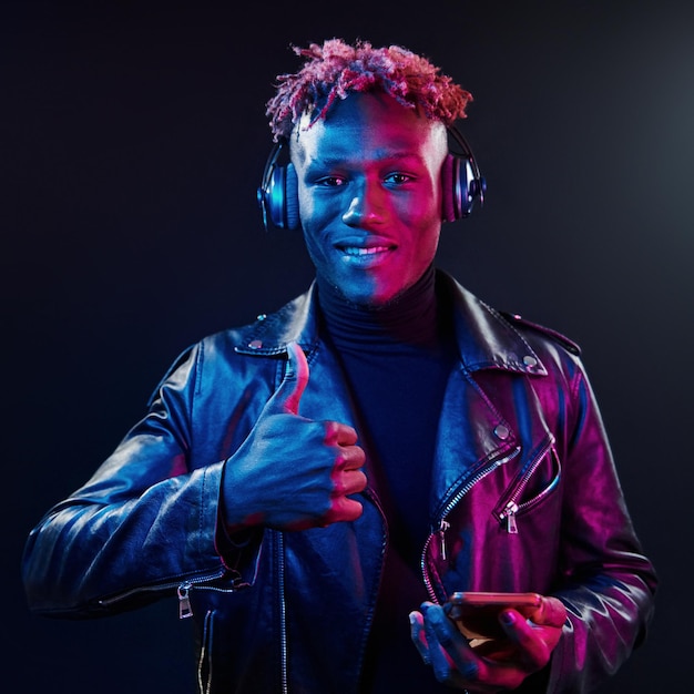 Dancing with headphones on Futuristic neon lighting Young african american man in the studio