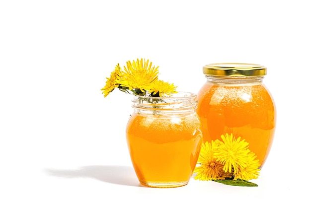 Dandelion jam or honey in the glass jar with fresh dandelion flowers isolated on white background