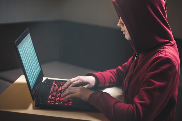 Dangerous hooded woman hacker breaks into personal data and infects system with a virus. Hacker attack, cyber security. Hacking and identity theft, fraud, scam concept