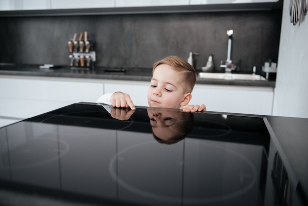 キッチンの危険な状況。電気オーブンで遊んでいる子供。