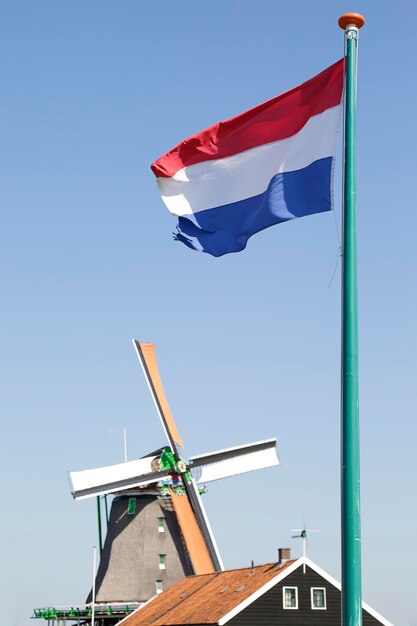 写真 デンマークの国旗とザンセ・シャンの風車が青い空を背景に オランダ