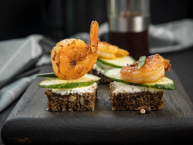 Danish open sandwich smorrebrod with shrimps cucumber and cream cheese on wooden serving board