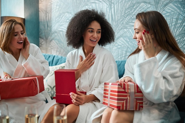 Dankbare jonge vrouwen die kerstcadeaus uitwisselen en openen