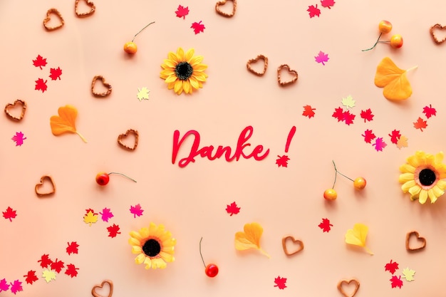 Danke means Thank you in German language. Fall decorations - yellow flowers, orange gingko leaves, maple leaf paper confetti