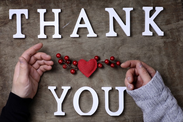 Foto dankwoord van witte houten letters op tafel en handen