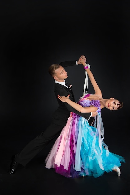 Dans ballroom paar in rode en blauwe kleurrijke jurk dans pose geïsoleerd op zwarte achtergrond. sensuele professionele dansers dansen wals, tango, slowfox en quickstep.