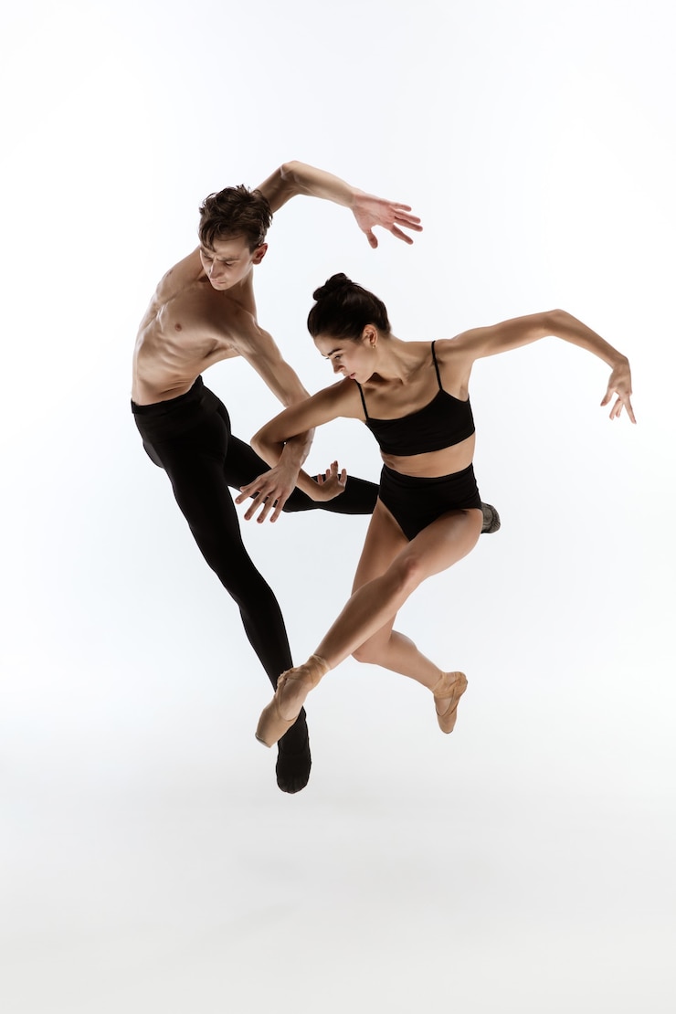 Foto dansen. jonge en sierlijke balletdansers in minimale zwarte stijl geïsoleerd op een witte studio achtergrond. kunst, actie, flexibiliteit, inspiratie, lichtheid van het lichaamsconcept. copyspace voor..