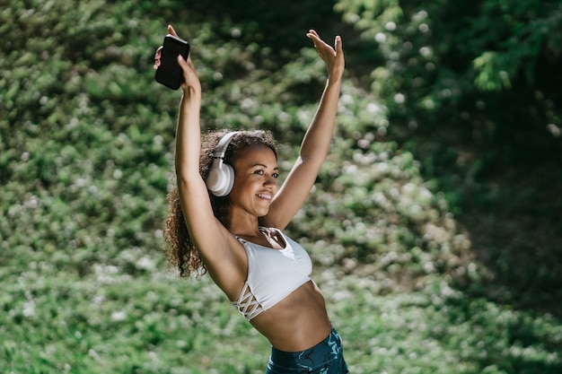 Dansende atletische vrouw die een koptelefoon draagt met haar smartphone