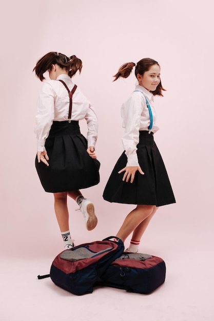 Dansende tweelingschoolmeisjes met dubbele staarten rug aan rug