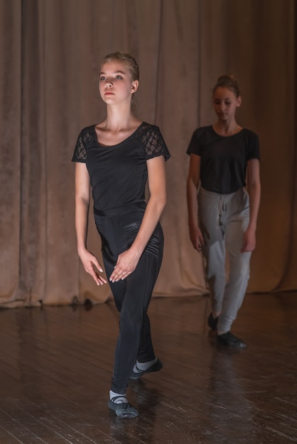 Dansers van jonge meisjes trainen dansbewegingen op het podium.