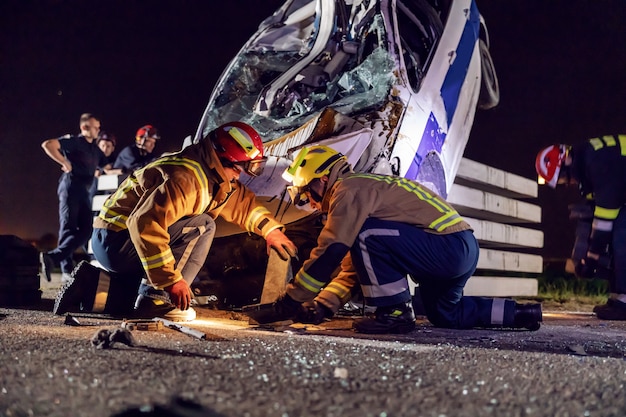 Dappere brandweerlieden die de man uit de gecrashte auto proberen te bevrijden.