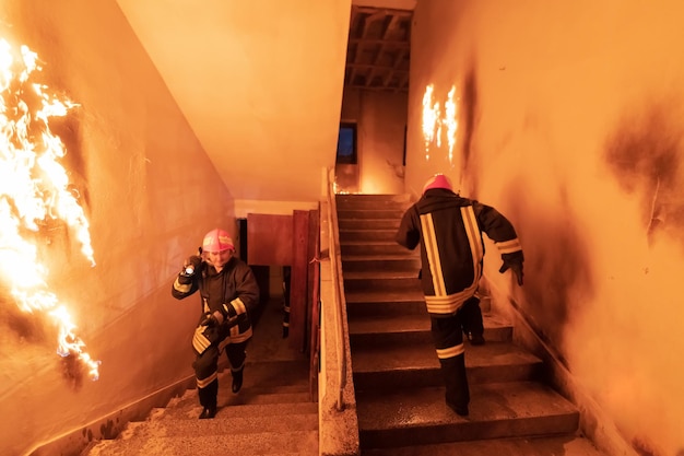 Dappere brandweerman gaat naar boven om mensen te redden en te redden in een brandend gebouw. Open vuur en vlam. Weinig licht hallo is selectieve focus stock foto.