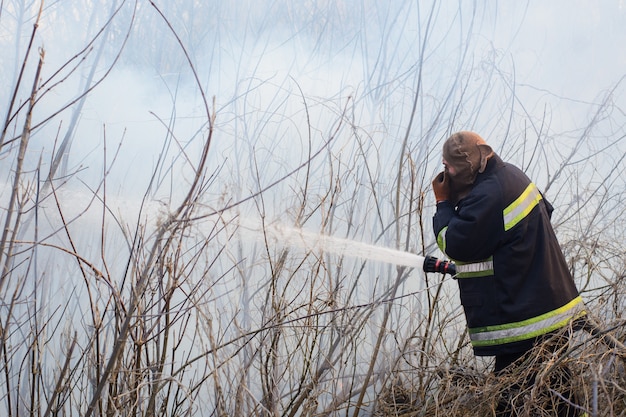 Dappere brandweerman staat in rook, vecht wildfire op het platteland