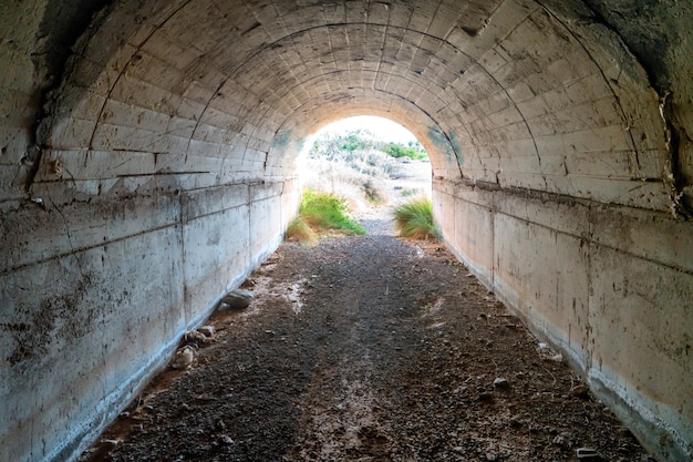 Темный заброшенный пустой туннель с ярким светом в конце