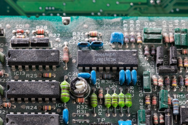 Dark background of old electronic circuit board closeup with dus