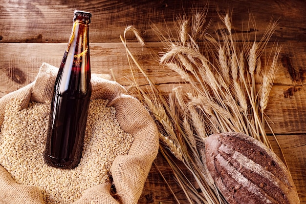 Dark beer in a bottle Beer in a grain bag Wheat and black bread Beer on a wooden background View from above