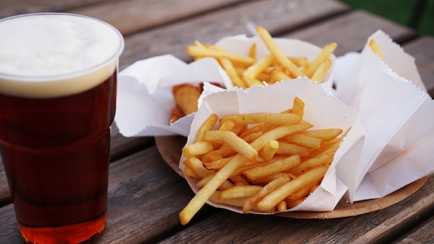 Birra scura e patatine fritte su un tavolo di legno food court cibo da asporto