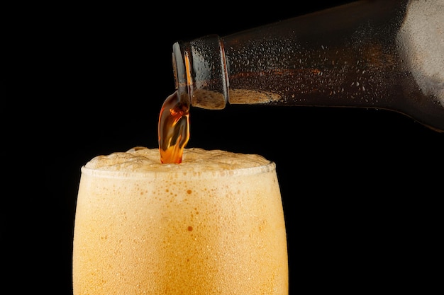 La birra scura viene versata in un bicchiere da una bottiglia