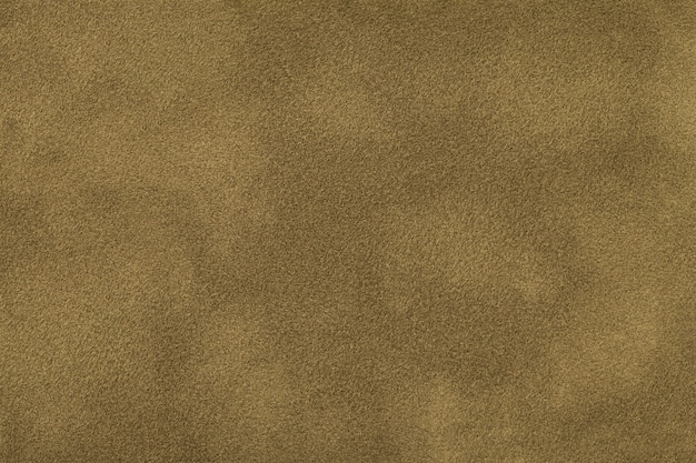 Photo dark beige matte background of suede fabric, closeup. velvet texture of seamless brown felt textile, macro.