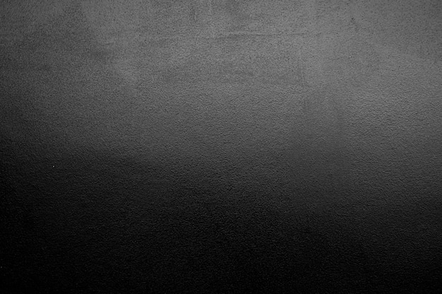 Dark black and gray blurred gradient cement wall background has a little abstract light sunlight shadow