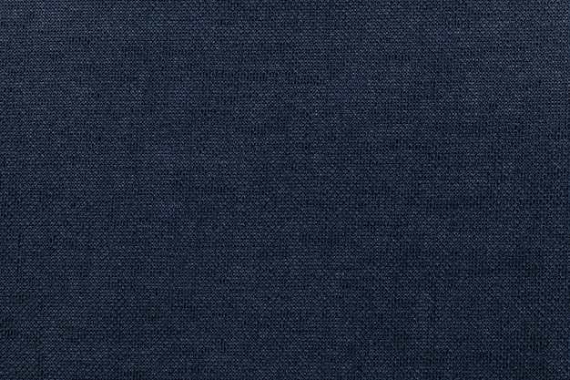 Dark blue background from a textile material. Fabric with natural texture. Backdrop.