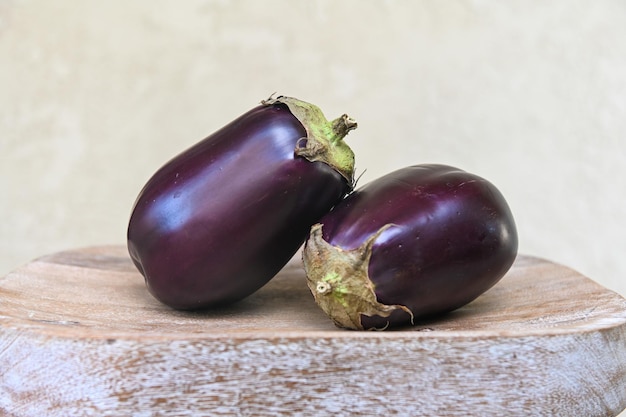 Dark blue eggplant on a white wooden textured board on a light background