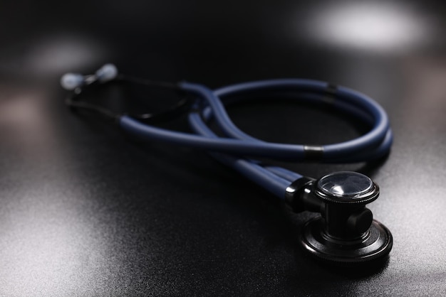 Dark blue medical stethoscope on black surface