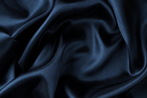 Dark blue silk satin wavy soft folds texture background.