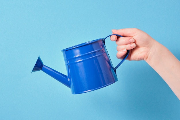 Dark blue watering can in hand