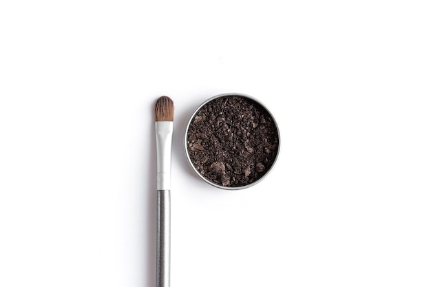 Dark brown face shadow in container and eye shadow or make-up brush. Makeup concept flat lay