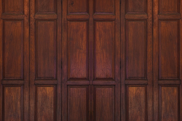 Dark brown old ancient wooden swing door background. Thailand traditional style. Using as wall or wallpaper.