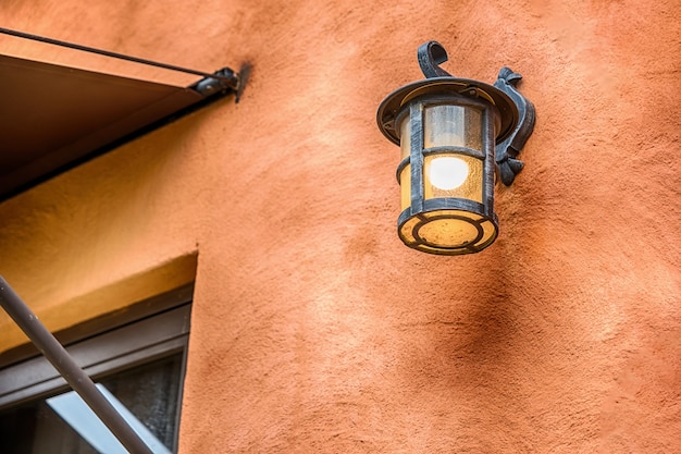 Apparecchio di illuminazione esterna marrone scuro contro un muro di pietra.