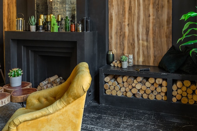 Dark brutal interior of sitting room decorated with wooden logs. yellow and grey soft armchairs, huge arc window and fireplace