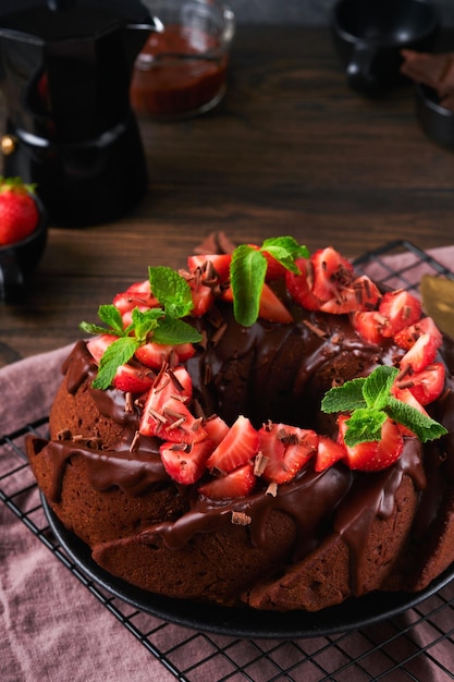 Dark Chocolate Bundt Cake met Ganache Icing en aardbei op donkere stenen of betonnen tafelachtergrond Feestelijke cake Selectieve focus