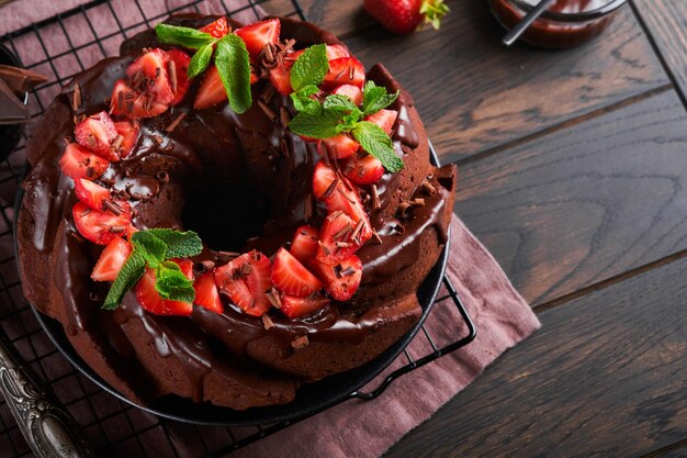 Torta bundt al cioccolato fondente con glassa di ganache e fragola su pietra scura o sfondo del tavolo in cemento torta festiva messa a fuoco selettiva